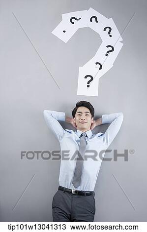 Stock Image - a business man with papers that has a question mark. Fotosearch