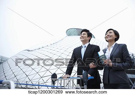 a businessman and businesswoman with baggage cart at the airport View Large Photo Image Stock Photo - a businessman and businesswoman with baggage cart at the airport. Fotosearch