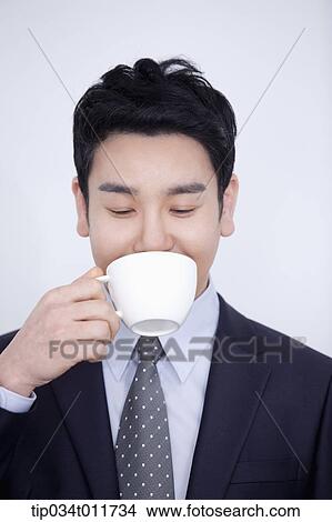 Picture - a businessman drinking cup of coffee. Fotosearch