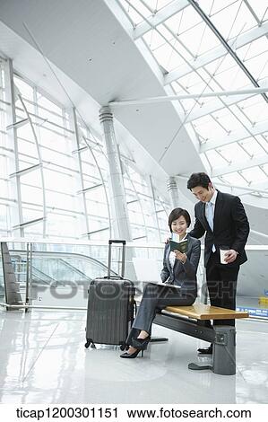 Stock Image - a businessman helping businesswoman with the boarding pass. Fotosearch
