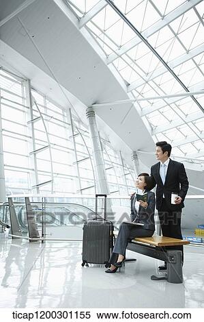 Stock Photography - a businessman helping businesswoman with the boarding pass. Fotosearch