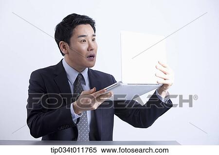 Stock Photography - a businessman holding a laptop. Fotosearch