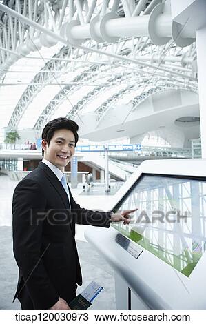Stock Image - a businessman looking at information device in the airport. Fotosearch