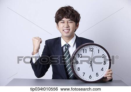 a businessman looking happy at desk with a clock View Large Photo Image Stock Photograph - a businessman looking happy at desk with a clock. Fotosearch