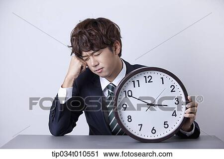 Stock Image - a businessman looking stressed with a clock. Fotosearch