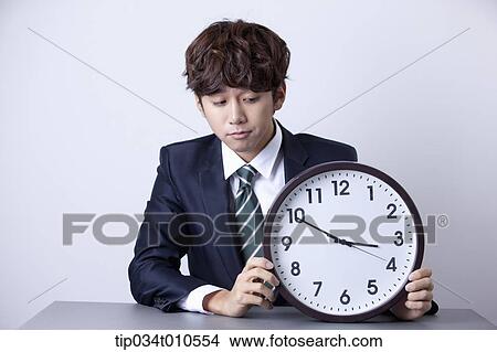 a businessman sitting at desk with a clock View Large Photo Image Picture - a businessman sitting at desk with a clock. Fotosearch