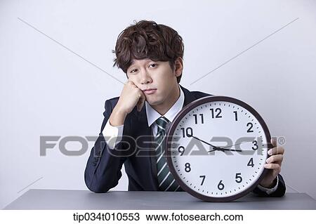 a businessman sitting at desk with a clock View Large Photo Image Stock Image - a businessman sitting at desk with a clock. Fotosearch
