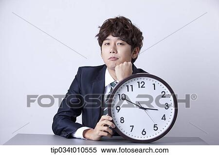 a businessman sitting at desk with a clock View Large Photo Image Stock Photography - a businessman sitting at desk with a clock. Fotosearch