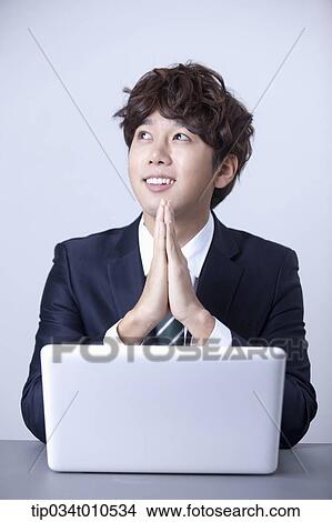 Picture - a businessman smiling while using a laptop. Fotosearch