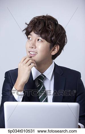 Stock Image - a businessman smiling while using a laptop. Fotosearch