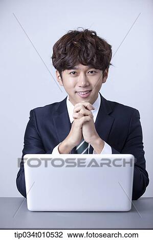 Stock Image - a businessman smiling while using a laptop. Fotosearch