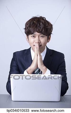 Stock Image - a businessman smiling while using a laptop. Fotosearch