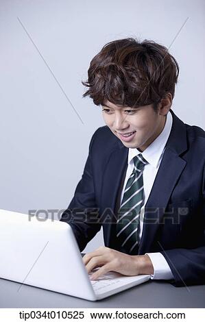 Stock Photography - a businessman smiling while using a laptop. Fotosearch