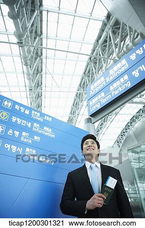 Stock Image - a businessman standing in front of a information board in the airport. Fotosearch