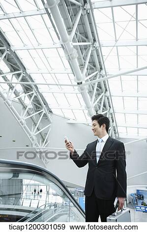 Stock Photo - a businessman taking escalator in the airport. Fotosearch