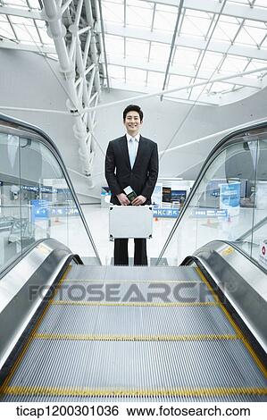 Stock Photograph - a businessman taking escalator in the airport. Fotosearch