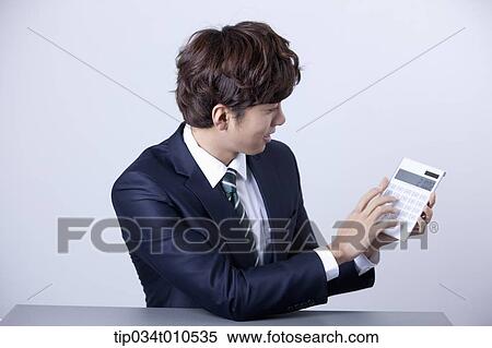 Stock Photography - a businessman using a calculator. Fotosearch