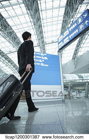 a businessman walking with suitcase in the airport View Large Photo Image Stock Photo - a businessman walking with suitcase in the airport. Fotosearch
