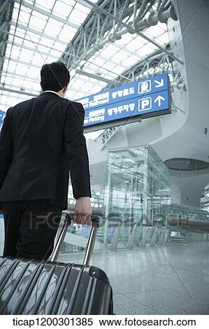 a businessman walking with suitcase in the airport View Large Photo Image Stock Photography - a businessman walking with suitcase in the airport. Fotosearch