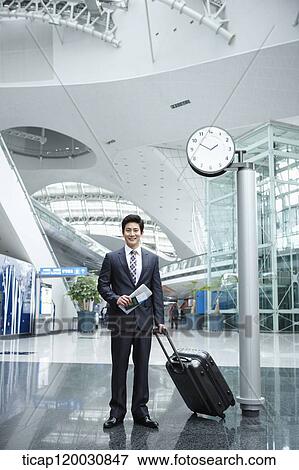 Stock Photo - a businessman with a suitcase in the airport. Fotosearch