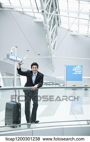 a businessman with suitcase greeting while leaning on fence in the airport View Large Photo Image Stock Photo - a businessman with suitcase greeting while leaning on fence in the airport. Fotosearch