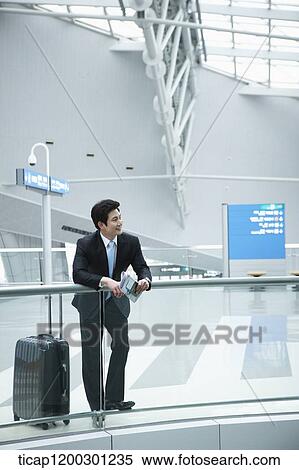 a businessman with suitcase leaning on fence in the airport View Large Photo Image Stock Photography - a businessman with suitcase leaning on fence in the airport. Fotosearch