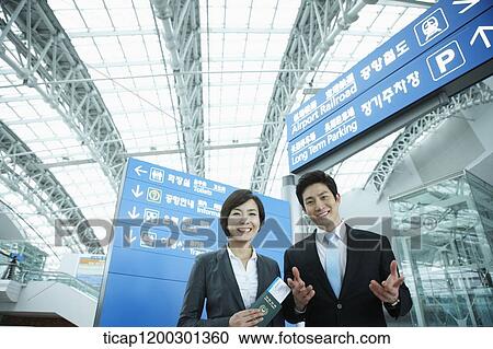 Stock Image - a businesswoman and businessman having a chat in the airport. Fotosearch
