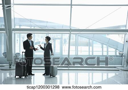 Stock Photo - a businesswoman and businessman having a chat in the airport. Fotosearch