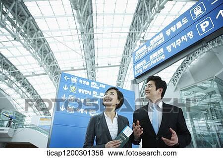 Stock Photo - a businesswoman and businessman having a chat in the airport. Fotosearch