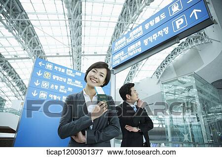 Stock Photo - a businesswoman and businessman posing in the airport. Fotosearch