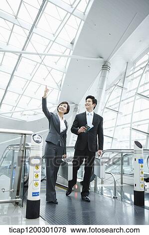 a businesswoman and businessman stepping out of escalator in the airport View Large Photo Image Stock Photo - a businesswoman and businessman stepping out of escalator in the airport. Fotosearch