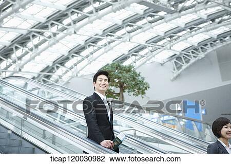 a businesswoman and businessman talking escalator in the airport View Large Photo Image Stock Image - a businesswoman and businessman talking escalator in the airport. Fotosearch