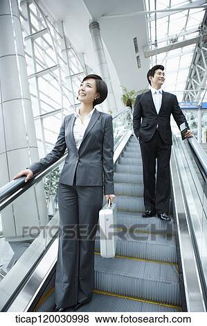 a businesswoman and businessman talking escalator in the airport View Large Photo Image Stock Photo - a businesswoman and businessman talking escalator in the airport. Fotosearch