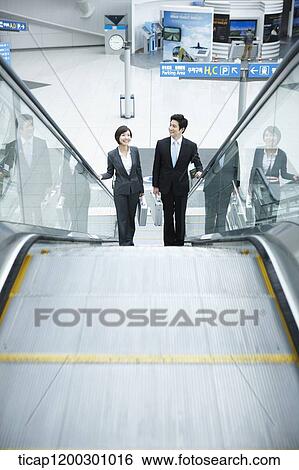 a businesswoman and businessman talking escalator in the airport View Large Photo Image Stock Photograph - a businesswoman and businessman talking escalator in the airport. Fotosearch