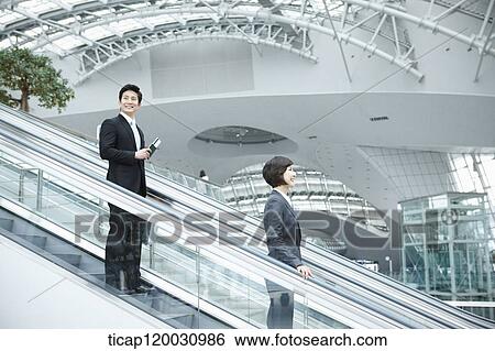 a businesswoman and businessman talking escalator in the airport View Large Photo Image Stock Photograph - a businesswoman and businessman talking escalator in the airport. Fotosearch