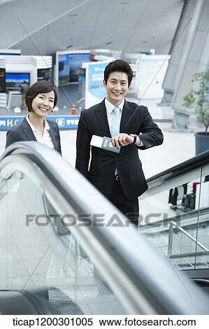 Stock Photography - a businesswoman and businessman talking escalator in the airport. Fotosearch