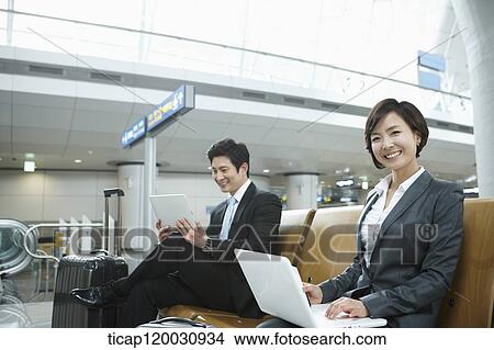 a businesswoman and businessman using devices in the airport View Large Photo Image Picture - a businesswoman and businessman using devices in the airport. Fotosearch