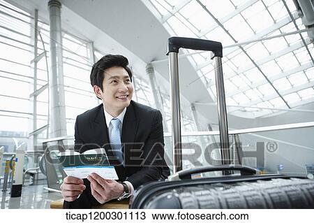 Stock Image - a businesswoman and businessman using laptop in the airport. Fotosearch