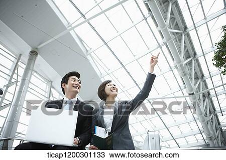a businesswoman and businessman using laptop in the airport View Large Photo Image Stock Image - a businesswoman and businessman using laptop in the airport. Fotosearch