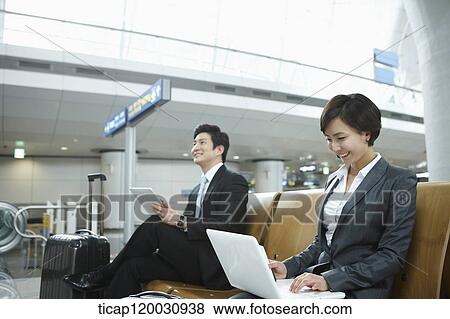 a businesswoman and businessman using devices in the airport View Large Photo Image Stock Photo - a businesswoman and businessman using devices in the airport. Fotosearch
