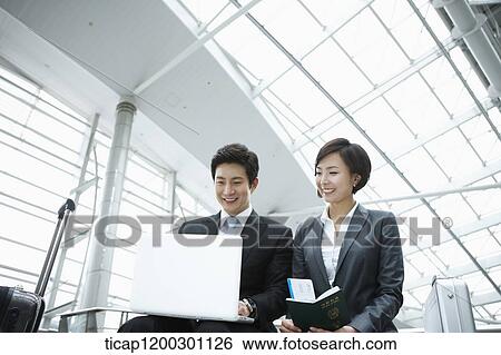 a businesswoman and businessman using laptop in the airport View Large Photo Image Stock Photograph - a businesswoman and businessman using laptop in the airport. Fotosearch