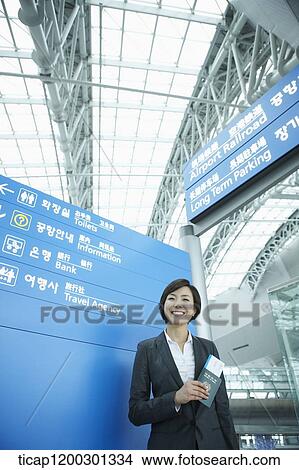 a businesswoman standing in front of a information board in the airport View Large Photo Image Picture - a businesswoman standing in front of a information board in the airport. Fotosearch