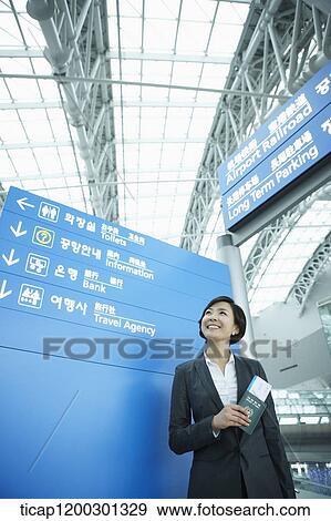 Stock Photo - a businesswoman standing in front of a information board in the airport. Fotosearch