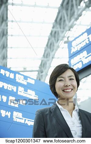 Stock Photo - a businesswoman standing in front of a information board in the airport. Fotosearch