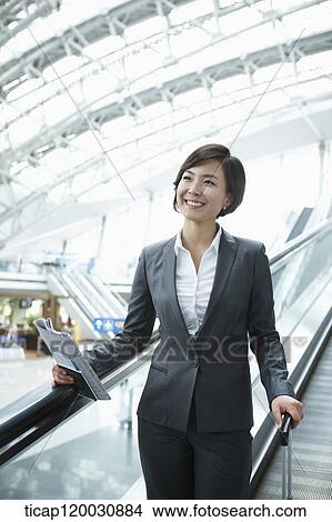 Picture - a businesswoman taking escalator in the airport. Fotosearch