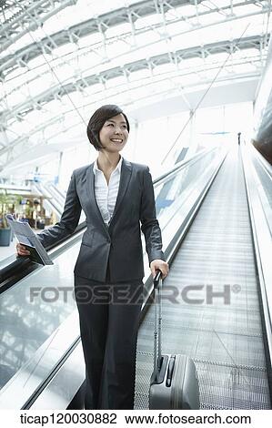 a businesswoman taking escalator in the airport View Large Photo Image Stock Image - a businesswoman taking escalator in the airport. Fotosearch