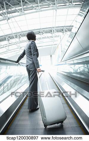 a businesswoman taking escalator in the airport View Large Photo Image Stock Photo - a businesswoman taking escalator in the airport. Fotosearch