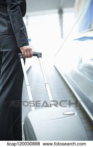 Stock Photo - a businesswoman taking escalator in the airport. Fotosearch