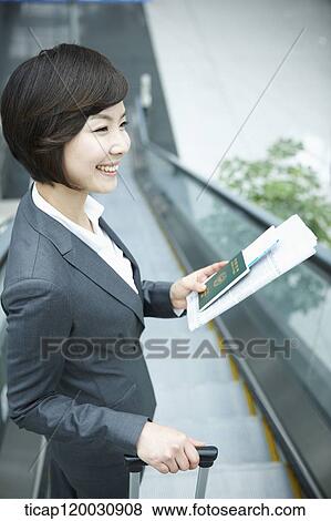 Stock Photo - a businesswoman taking escalator in the airport. Fotosearch