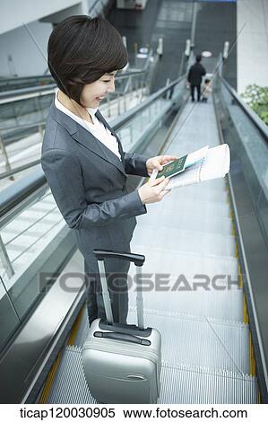 Stock Photography - a businesswoman taking escalator in the airport. Fotosearch
